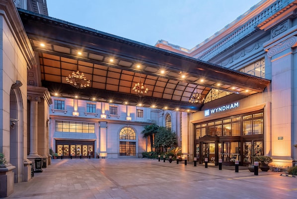 A grand hotel entrance with a covered walkway, large windows, and a prominent Wyndham sign.