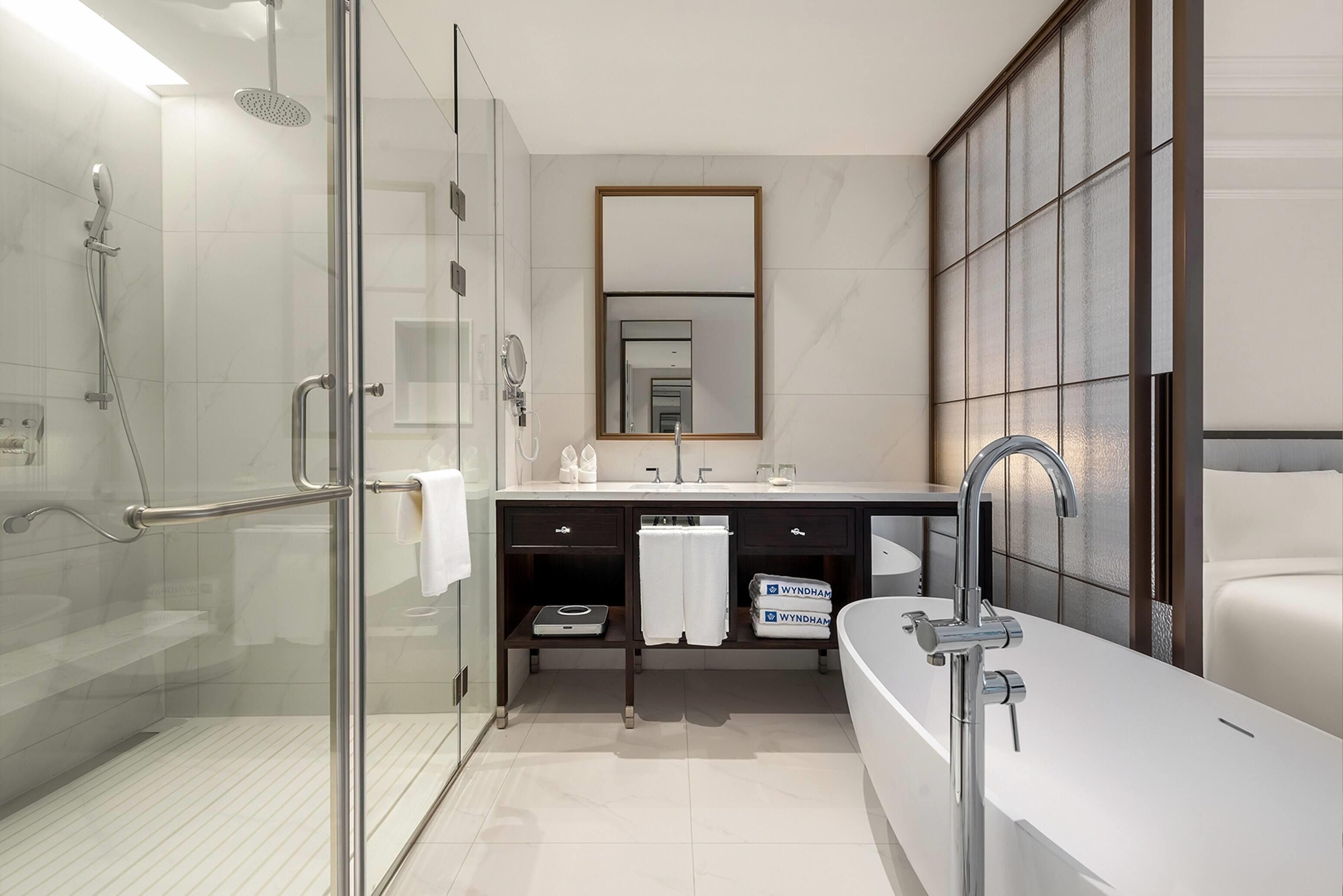 A modern bathroom with a glass-enclosed shower, a large mirror, a white sink, and a bathtub.