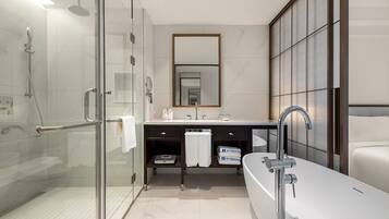 A modern bathroom with a glass-enclosed shower, a large mirror, a white sink, and a bathtub.