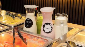 Un bufé con diversas opciones de comida y bebida, incluyendo un batido de yogur y un smoothie verde.