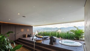 A modern outdoor relaxation area with a hot tub, seating, and a view of mountains. - Diez Hotel Categoria Colombia (Medellín)