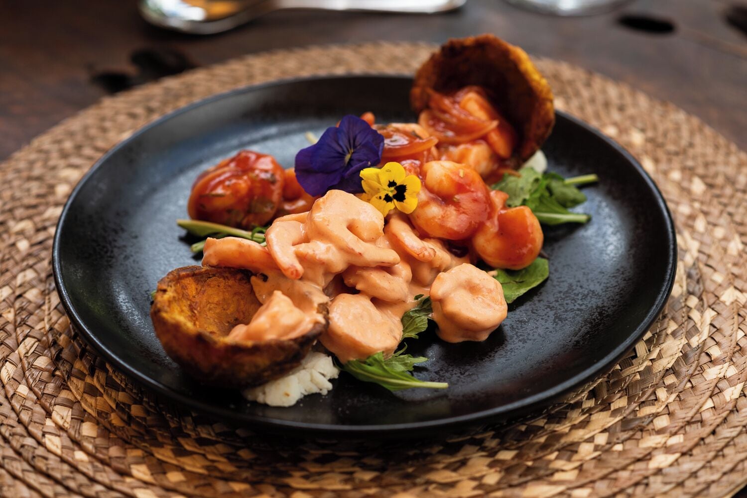 Een bord eten met garnalen, een tomaat en een bloemversiering.