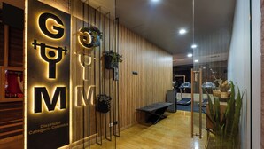 A gym area with a mirrored wall, exercise equipment, and a wooden panel design. - Diez Hotel Categoria Colombia (Medellín)