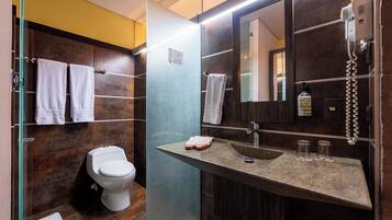 Un baño moderno con inodoro, lavamanos con espejo y secador de pelo montado en la pared.