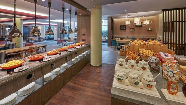 En modern hotellrestaurang med en buffé, som innehåller ett varierat utbud av mat och tillbehör.