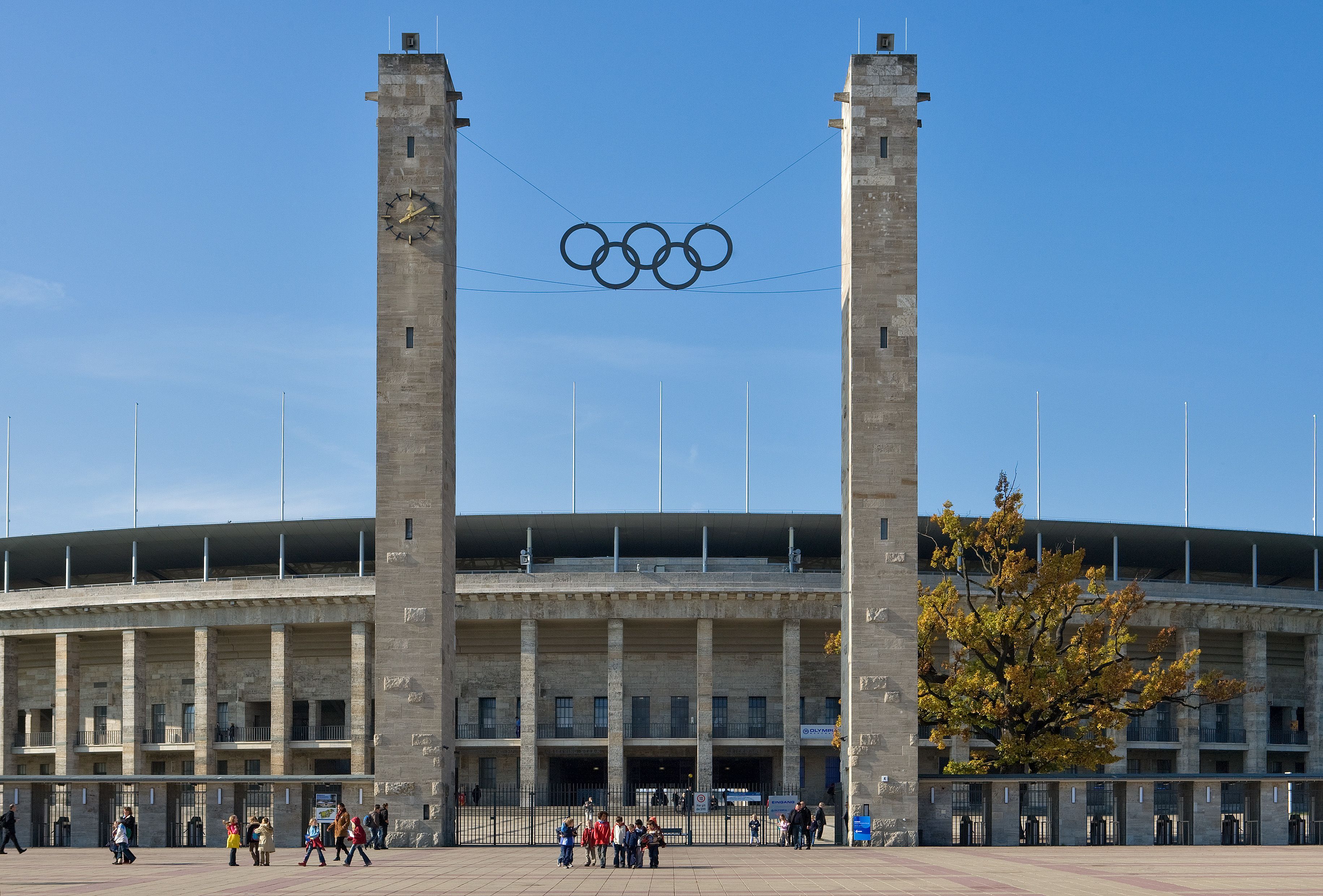 Un edificio amplio y moderno con un logotipo destacado de los anillos olímpicos sobre la entrada.