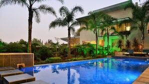 Una piscina de diseño moderno, rodeada de palmeras y abundante vegetación.