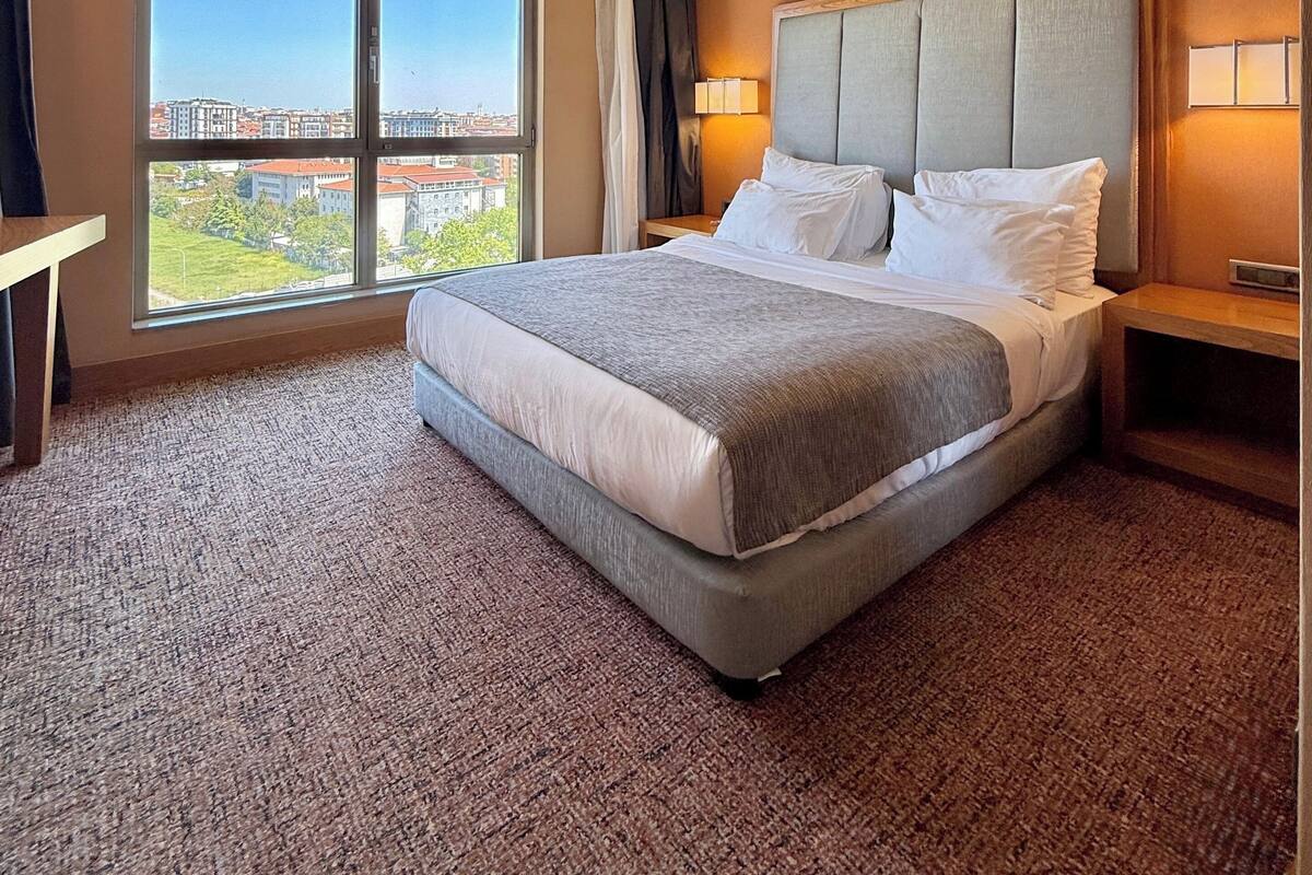 Ein Hotelzimmer mit einem großen Bett, Blick auf die Stadt und einer Deckenleuchte.