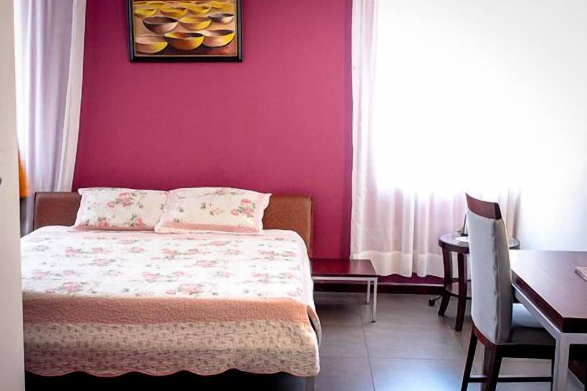 A bedroom with a bed, a desk, and a chair.