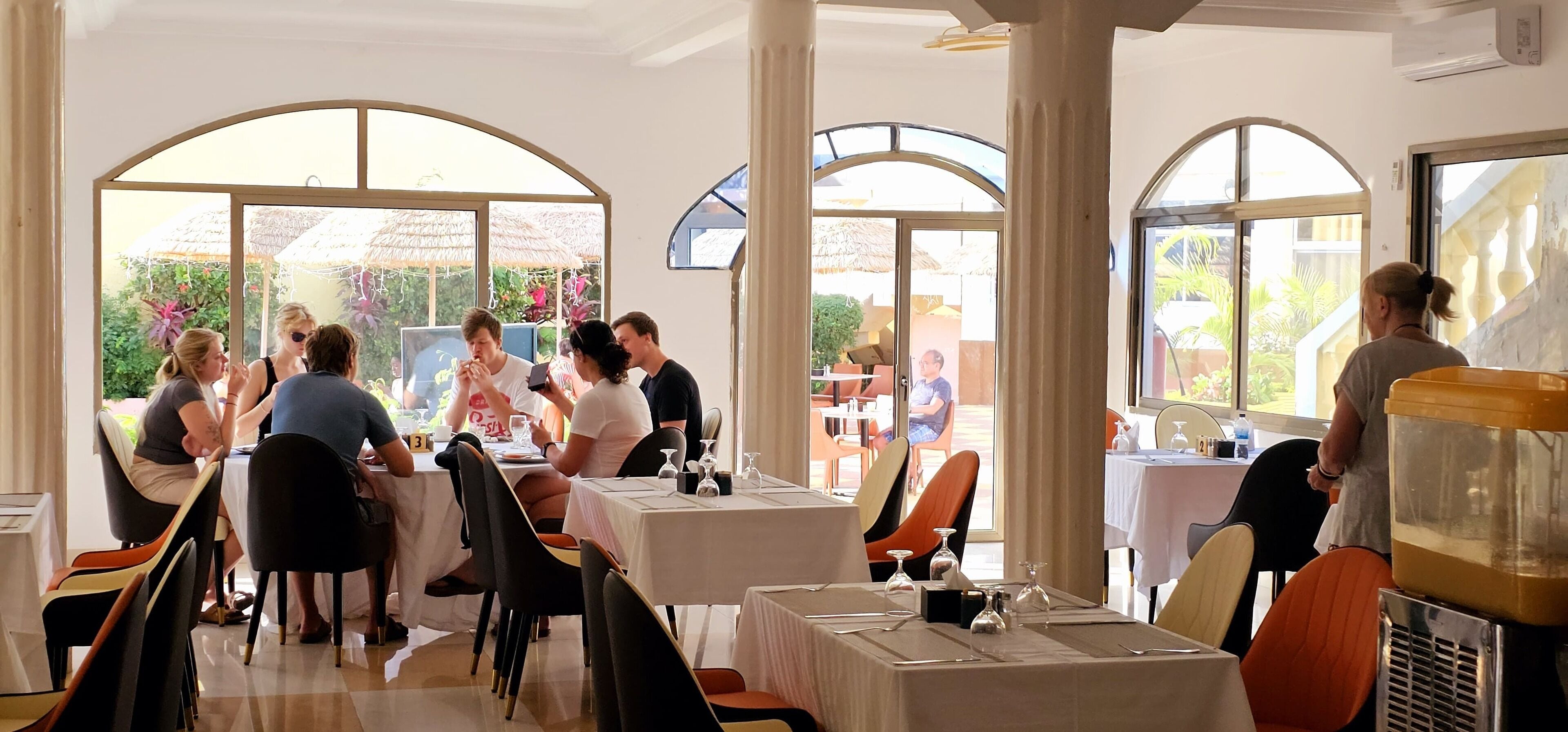 Un restaurante con mesas y sillas, ventanas amplias y vistas al exterior.