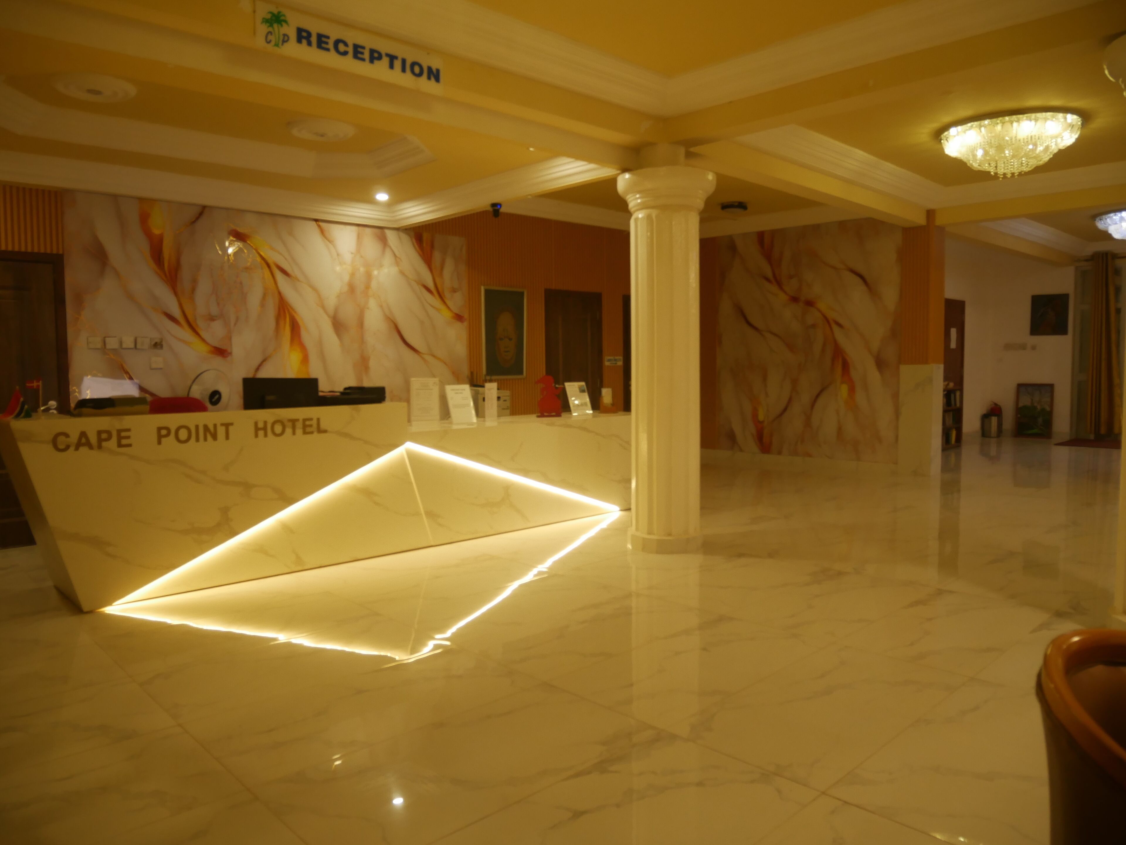 A reception desk at Cape Point Hotel with a marble design, a chandelier, and a modern interior.
