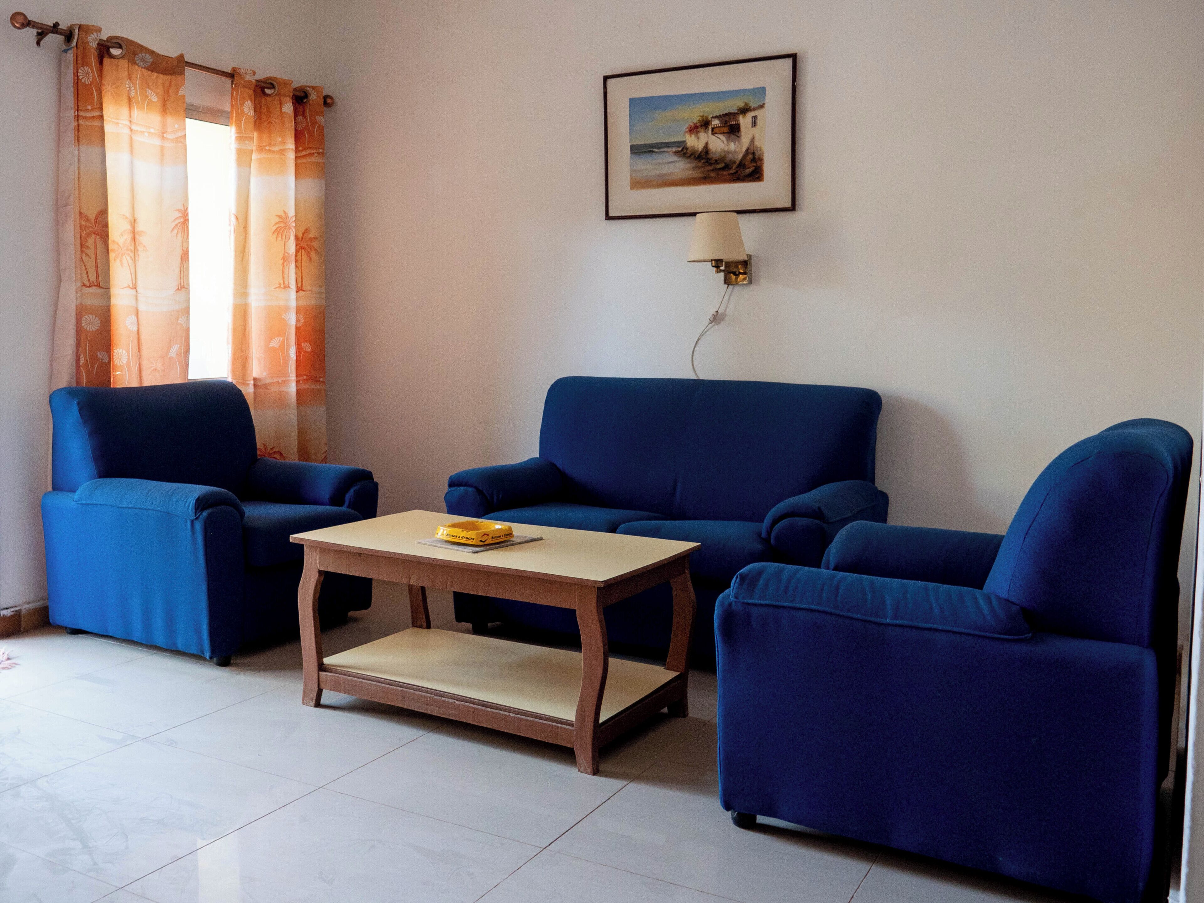 A room with two blue sofas, a wooden coffee table, and a painting on the wall.