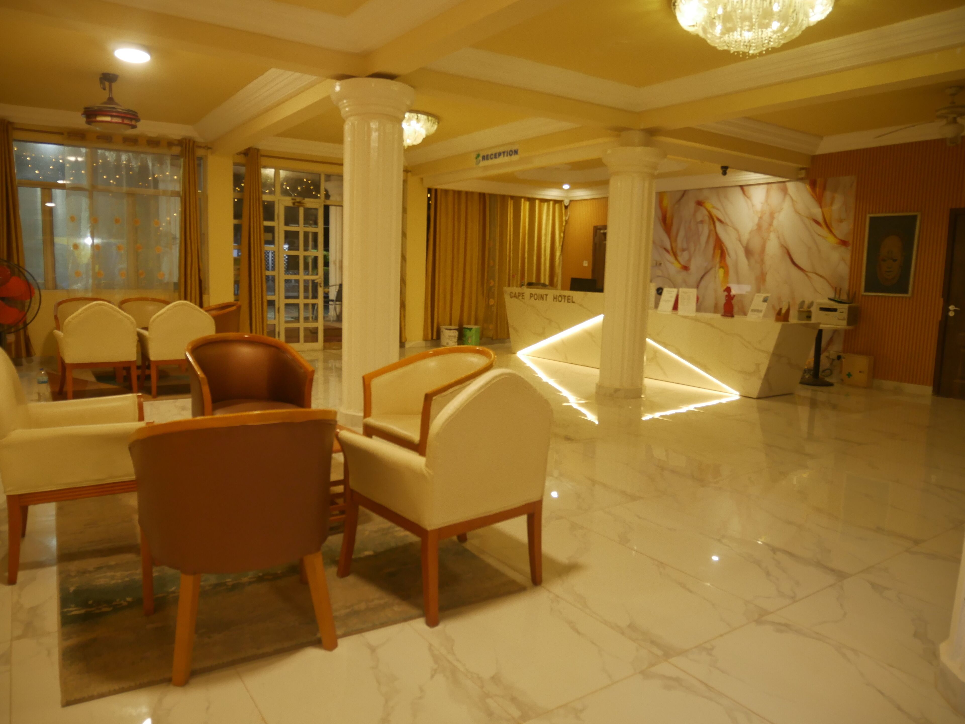 Un vestíbulo de hotel con suelo de mármol, mostrador de recepción y zona de estar con sillas.