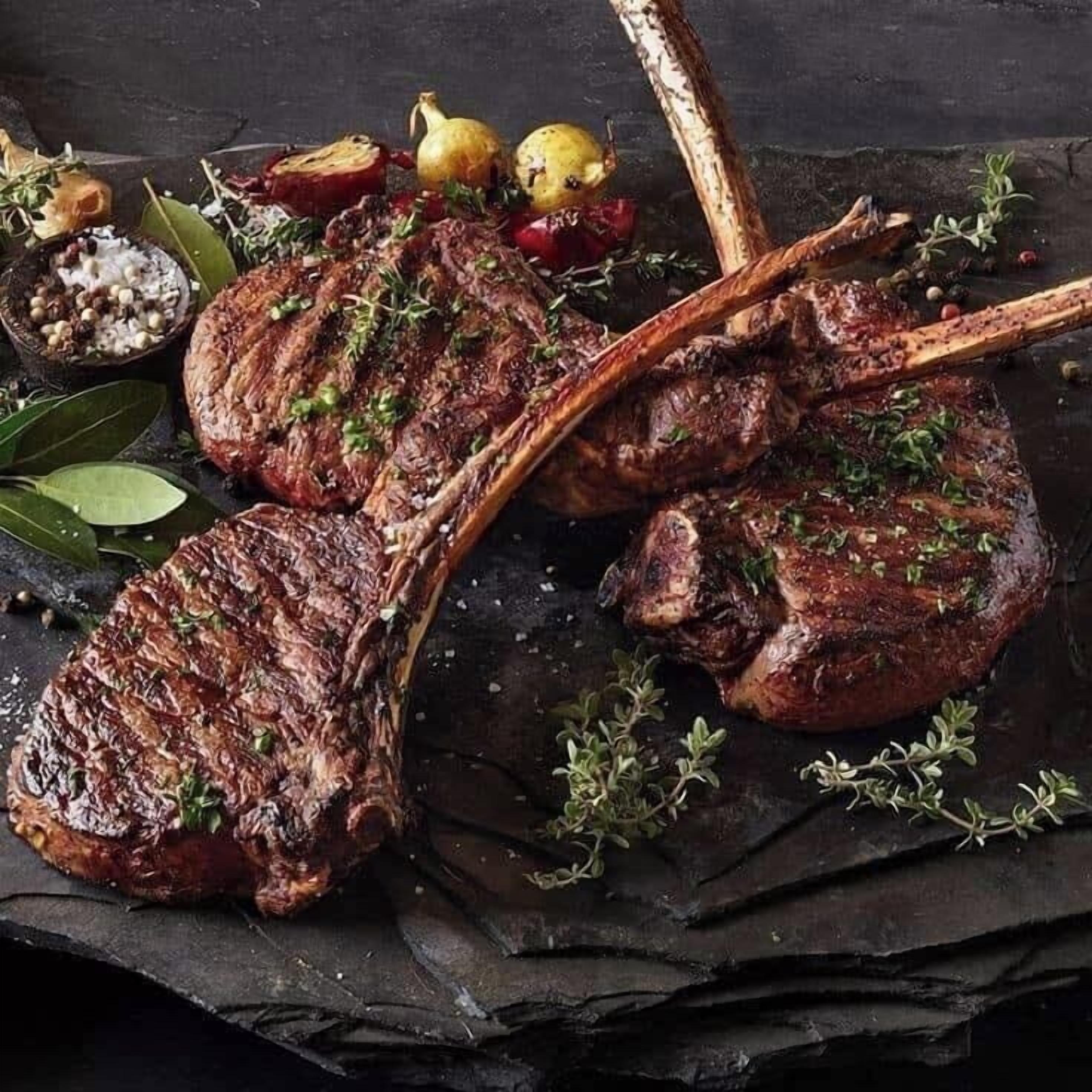 Un steak avec os, agrémenté d’herbes et entouré de légumes et d’épices.
