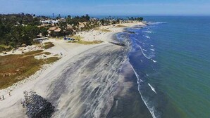 Una playa costera con arena, algunos edificios y cielo despejado.