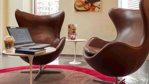 A modern interior with two leather chairs, a laptop, a Starbucks cup, and a small table with a menu. - ibis Sharq Kuwait (Kuwait City)