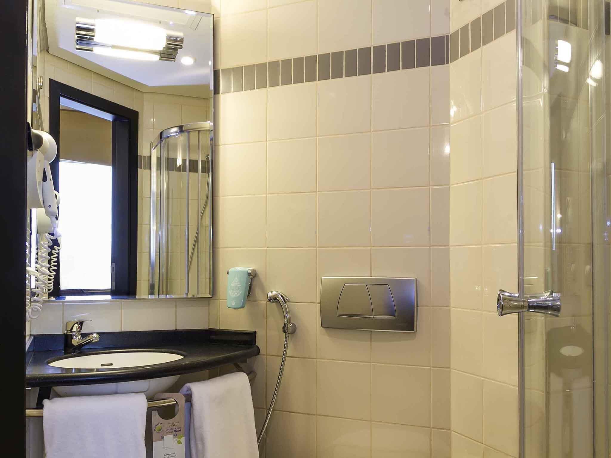 A bathroom with a sink, mirror, towel rack, shower, and a glass door.