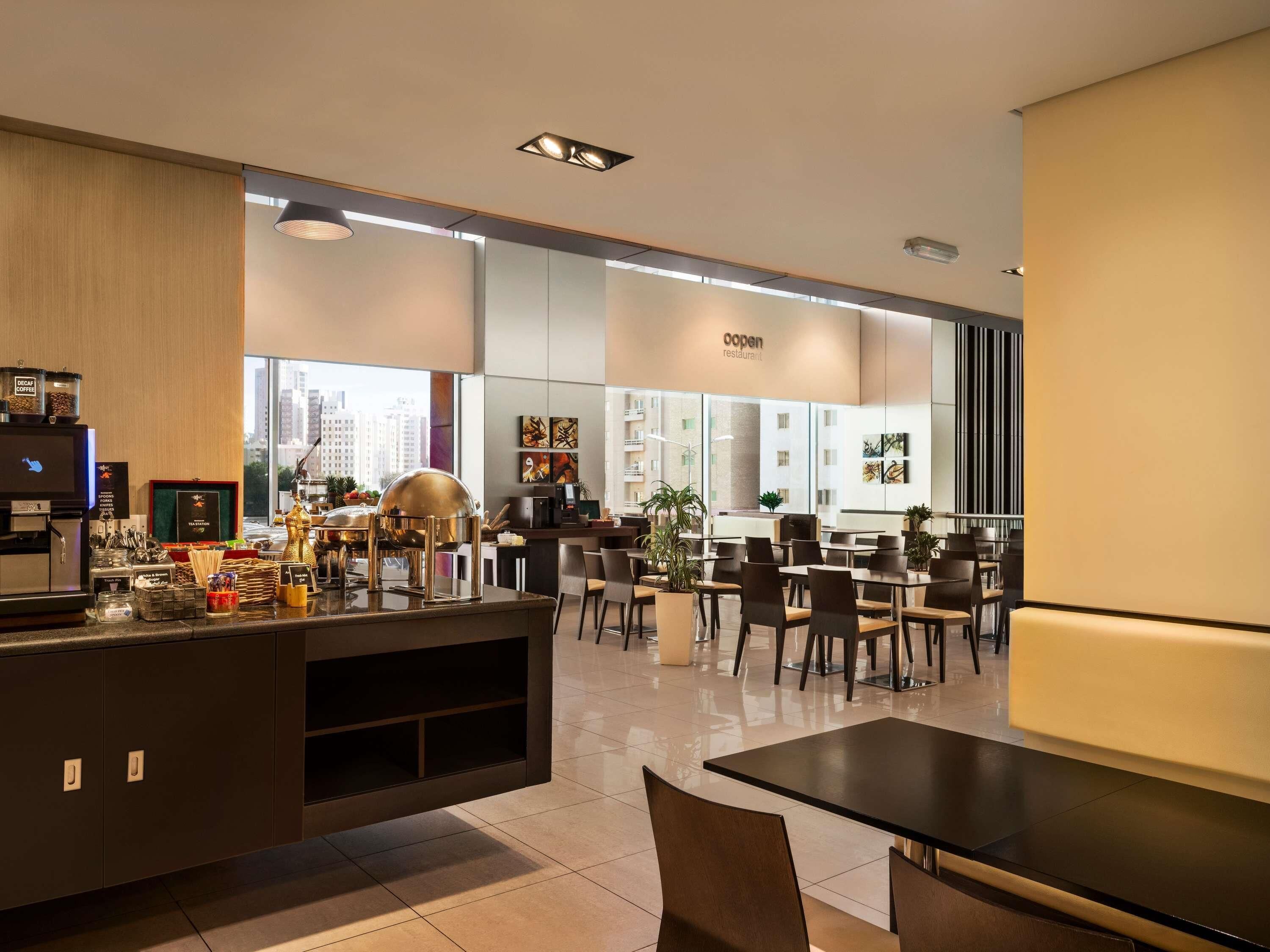 Un restaurant moderne doté d’un bar, de tables et de grandes fenêtres offrant une vue sur la ville.