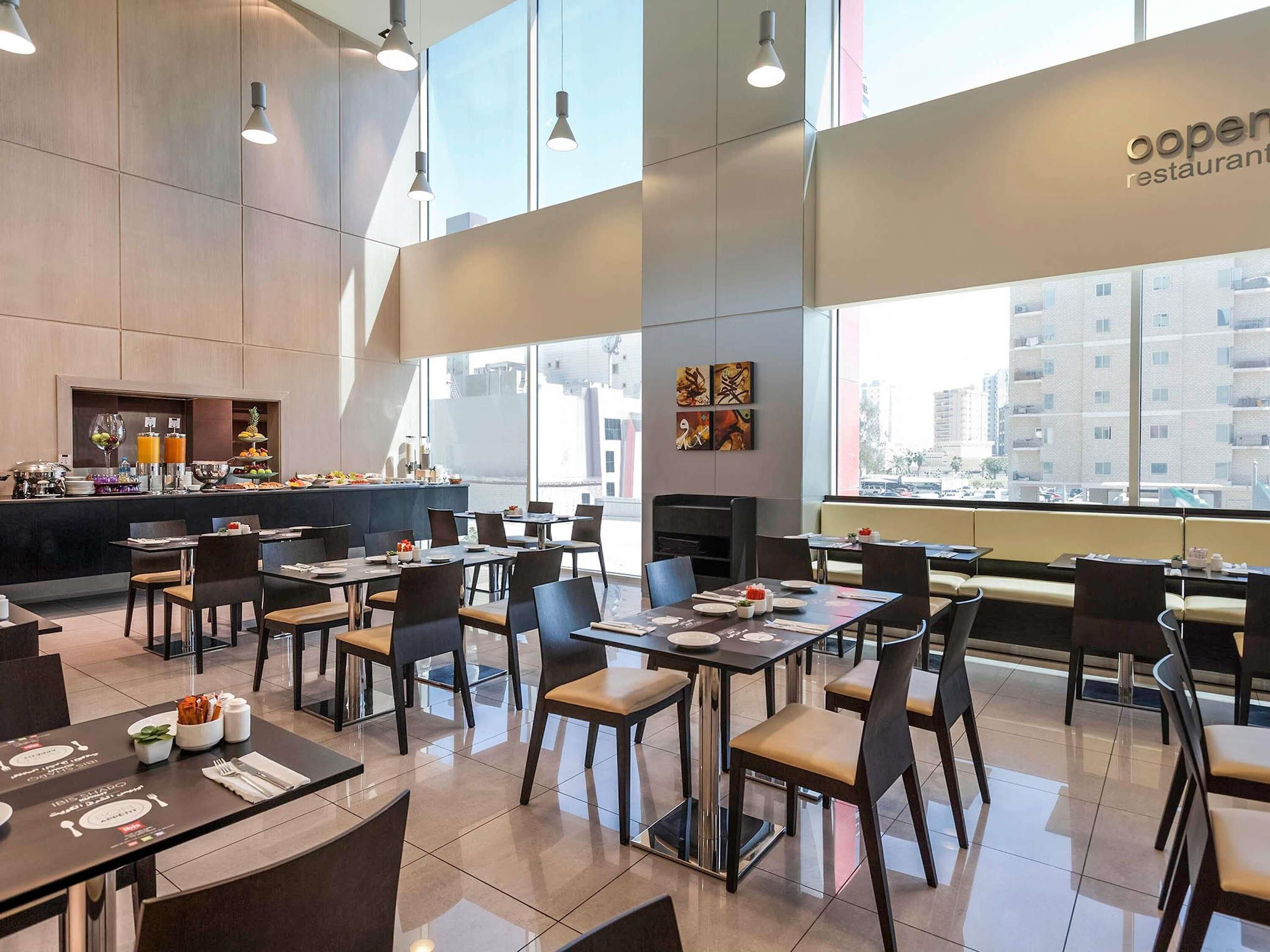 Un restaurante moderno con techo alto, ventanas amplias y una zona de bufé.