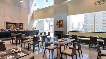 Un restaurante moderno con techo alto, ventanas amplias y una zona de bufé.