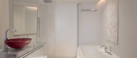 A modern bathroom with a glass-enclosed shower, a red vessel sink, and a large white bathtub.