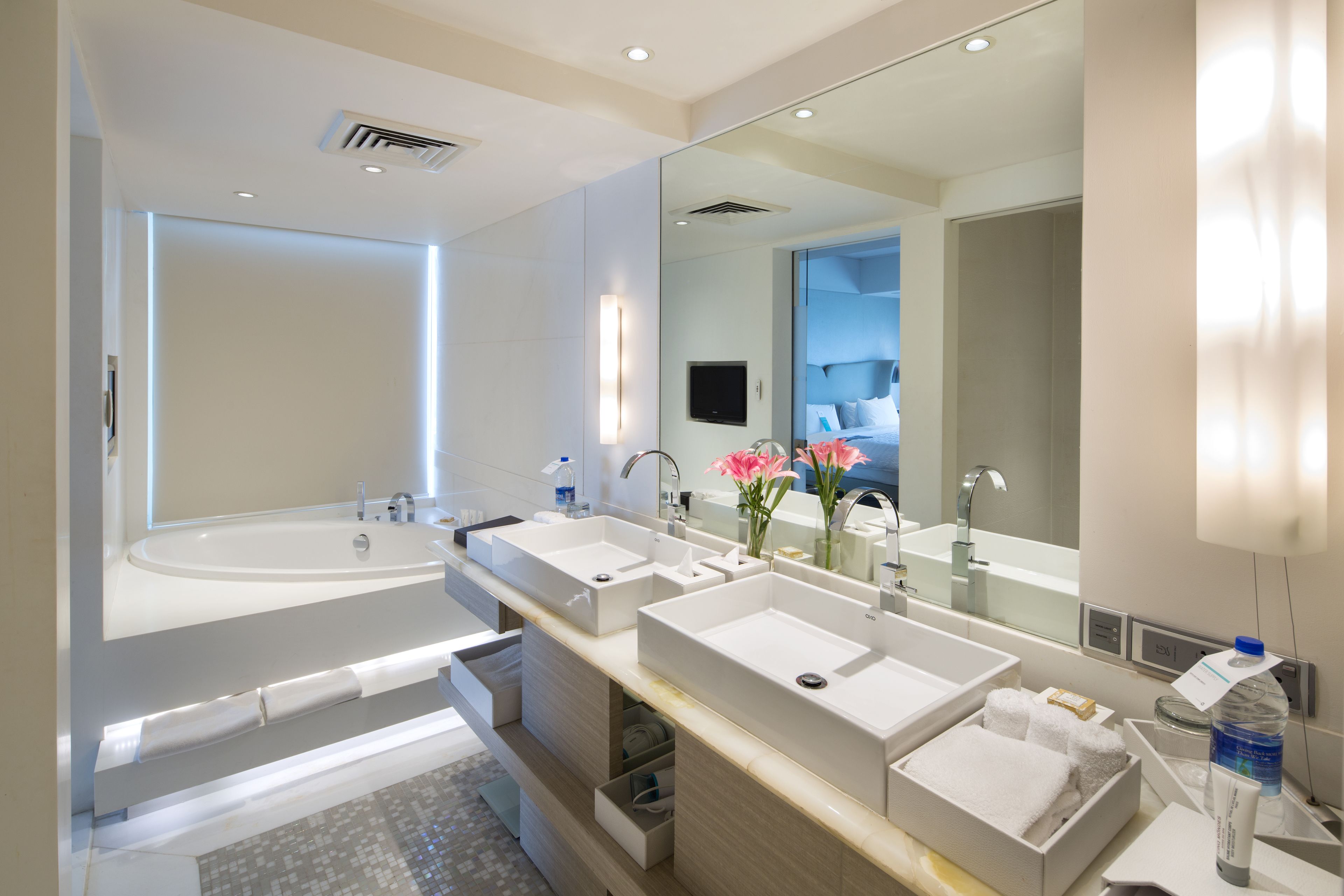 A modern bathroom with a large bathtub, two sinks, and a mirror.