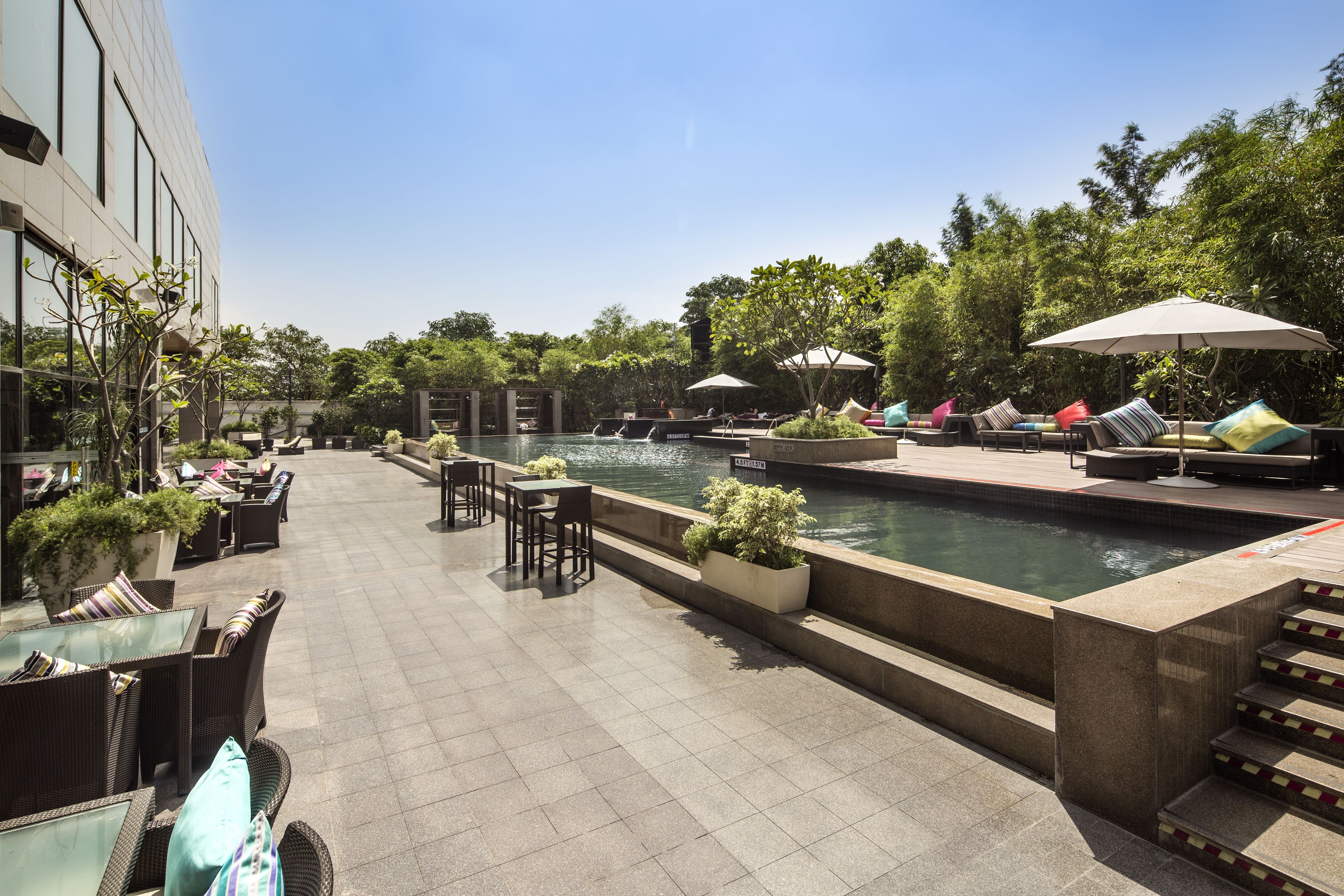 Ein Poolbereich mit Liegestühlen, Sonnenschirmen und Sitzgelegenheiten im Freien.