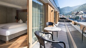 A balcony with a bed, wicker chairs, and a table. - Hotel Sonnenhof (Gerlos)