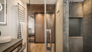 A modern bathroom with a glass shower enclosure, a wooden vanity, and a visible shower area. - Hotel Sonnenhof (Gerlos)