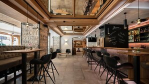 A modern bar area with wooden beams, black bar stools, and a chalkboard menu. - Hotel Sonnenhof (Gerlos)