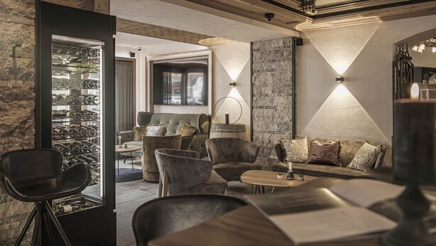 A modern interior with a wine rack, seating area, and ambient lighting. - Hotel Sonnenhof (Gerlos)