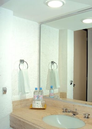 A bathroom with a beige sink, two towel rings, and a mirror reflecting the room. - Hotel Los Cocos (Chetumal)