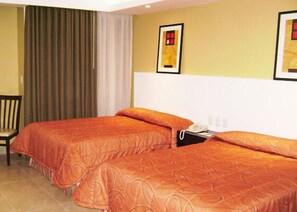 A hotel room with two beds, a chair, a bedside table with a phone, and a framed picture on the wall. - Hotel Los Cocos (Chetumal)
