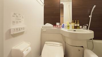 A bathroom with a toilet, sink, and shower. There are toiletries on the sink counter.