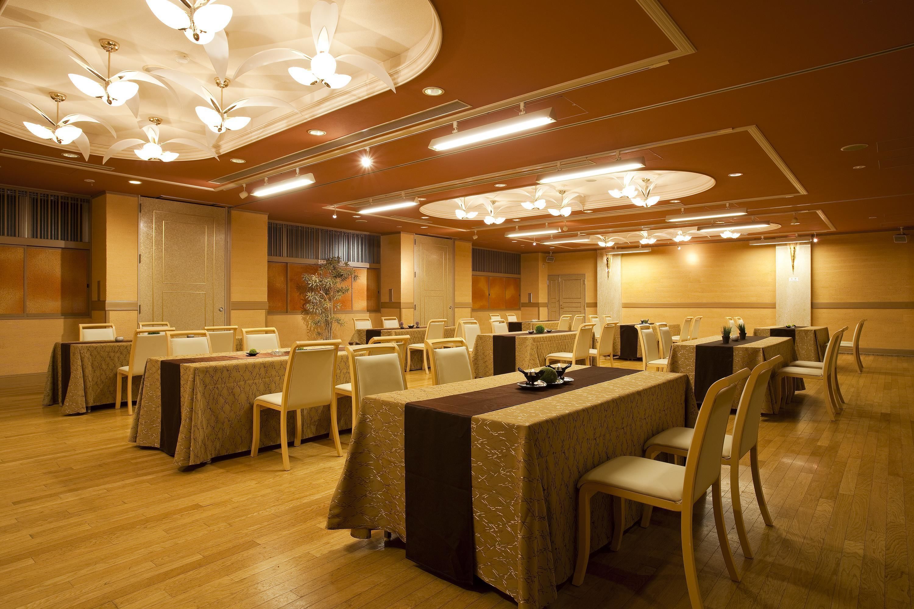 A conference room with multiple tables and chairs, ceiling lights, and a decorative plant.