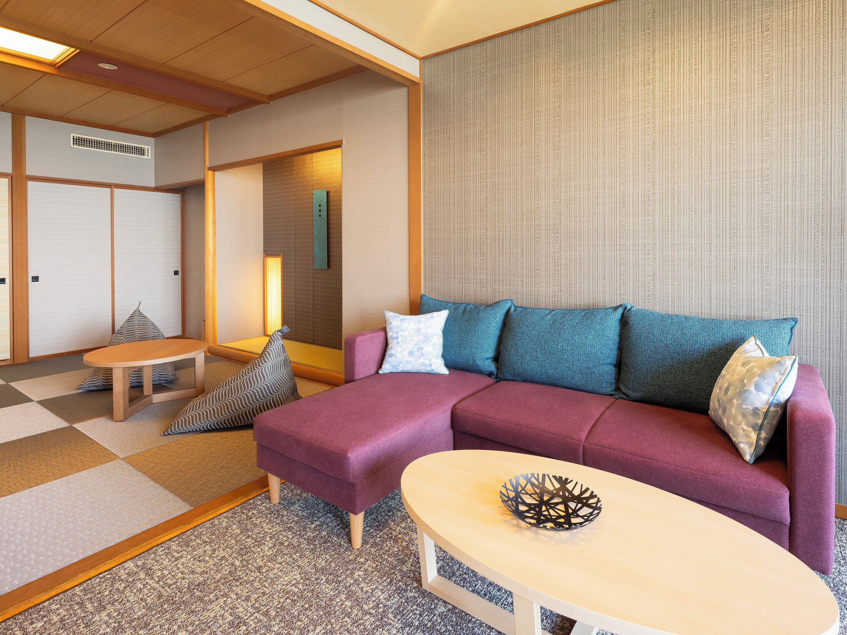 A modern living room with a purple sectional sofa, a round coffee table, and a patterned rug.