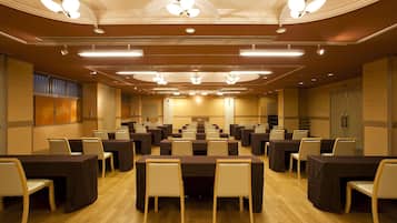 A conference room with multiple tables and chairs, ceiling fans, and recessed lighting.