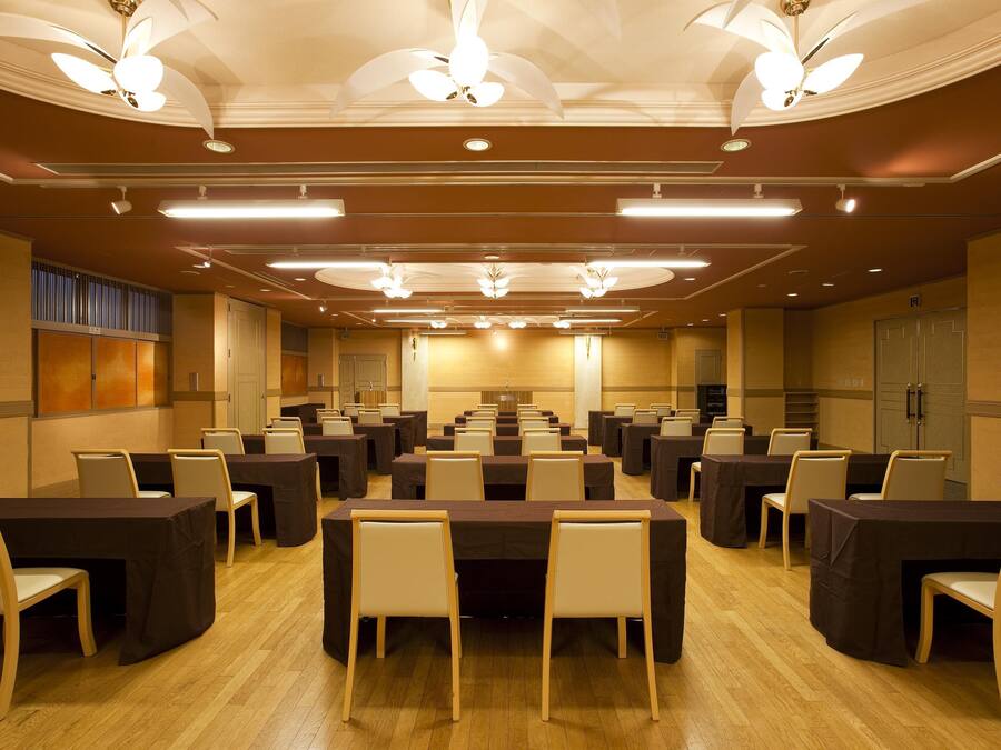 A conference room with multiple tables and chairs, ceiling fans, and recessed lighting.