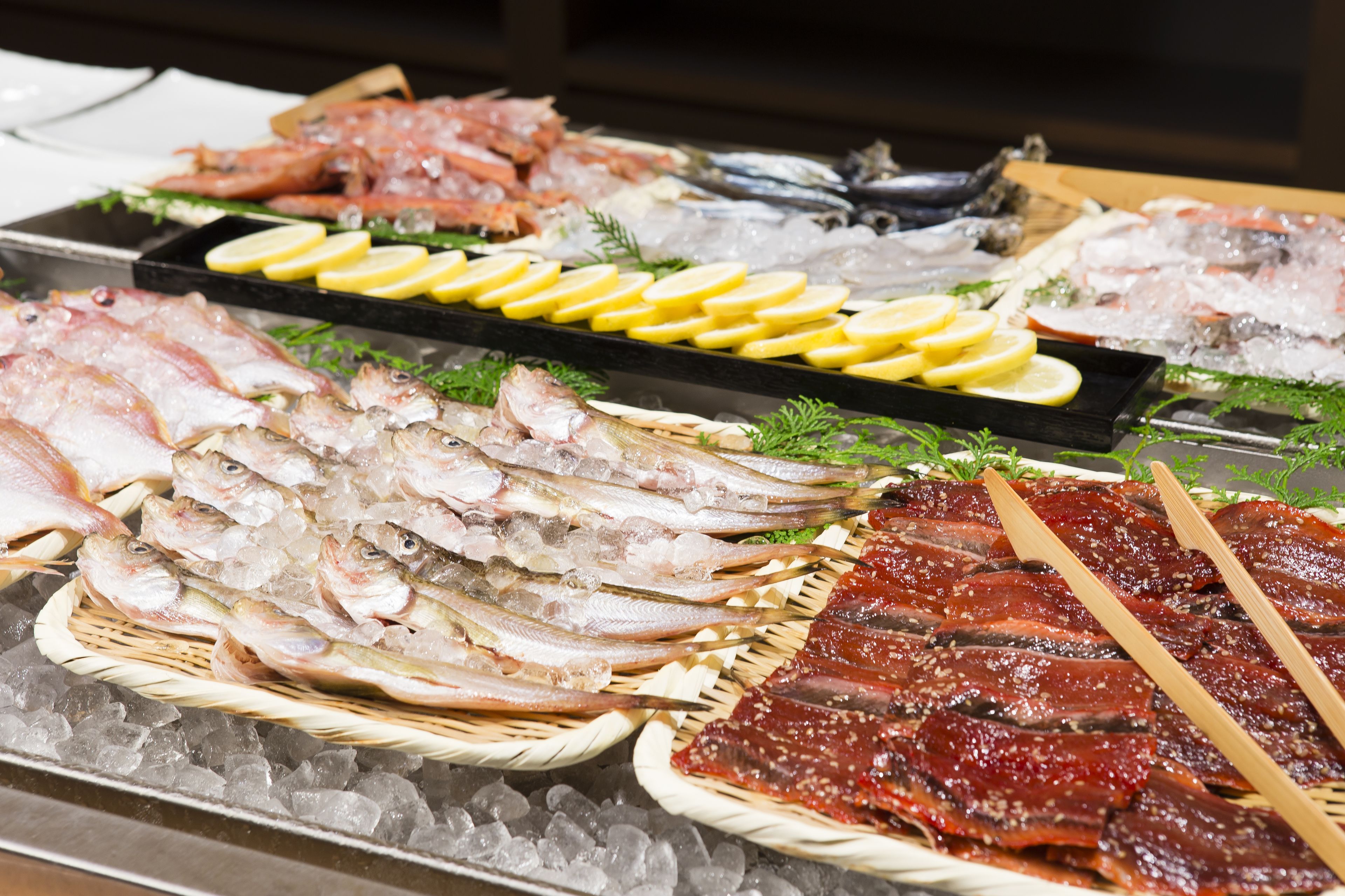 A variety of seafood displayed on ice with wooden tongs.