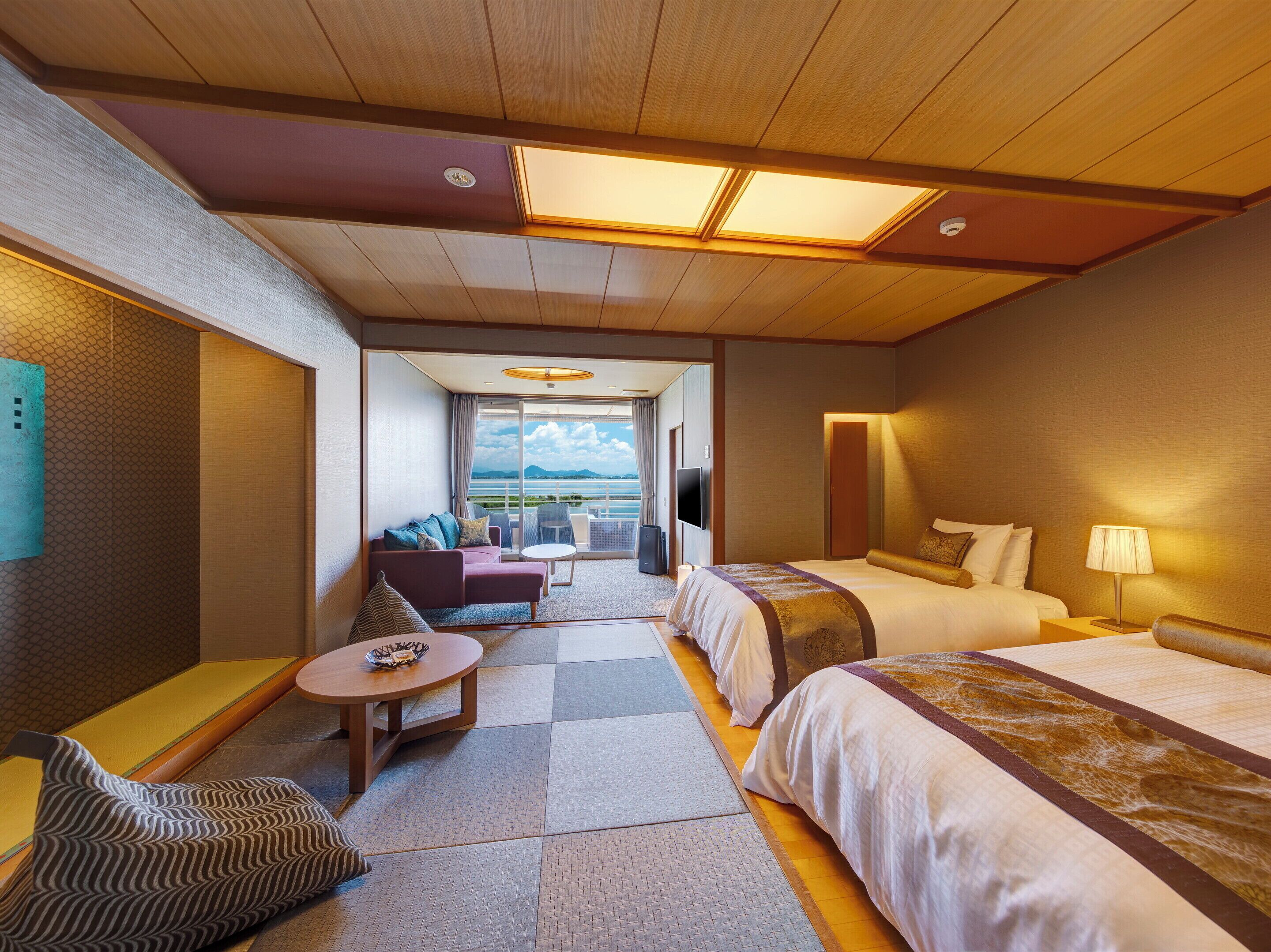 Habitación de hotel con cama, sofá, una mesita y vista al mar.
