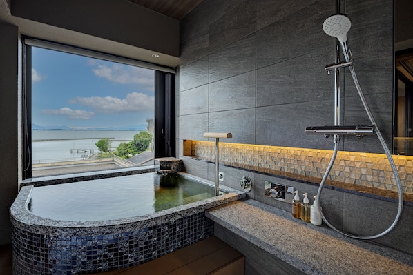 A modern bathroom with a large bathtub, a shower, and a view of the sea. - Biwako Ryokusuitei (Otsu)