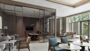 A modern hotel room with a large sliding glass door, a flat-screen TV, a dining area with a table and chairs, and a seating area with sofas and armchairs.