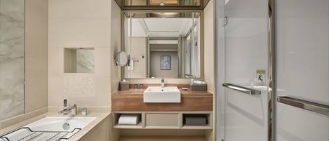 A modern bathroom with a marble wall, a bathtub, a sink with a wooden countertop, and a mirror.