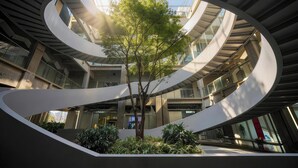 A modern building with a central spiral staircase, a tree, and surrounding greenery. - Shanghai Marriott Hotel Yangpu Riverside (Shanghai)