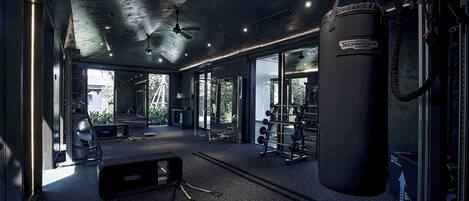 A modern gym with ceiling fans, a punching bag, and various exercise equipment.