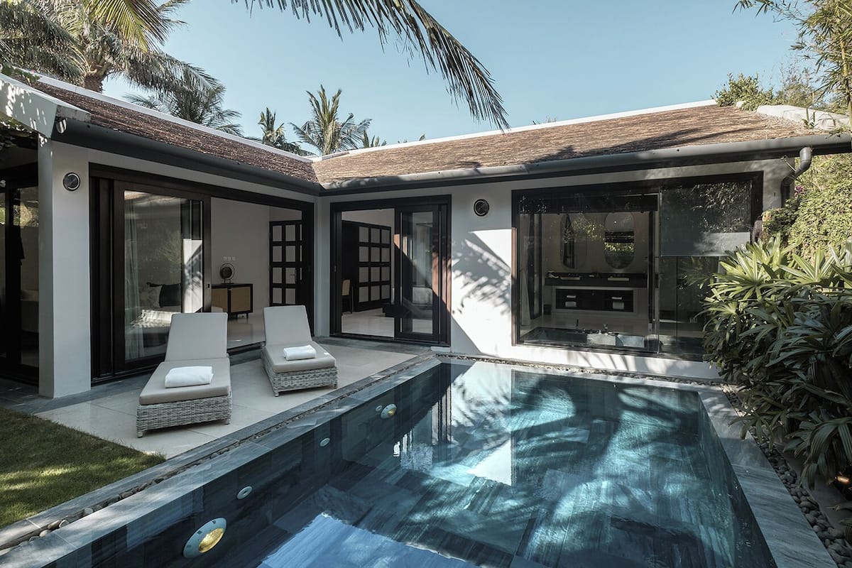 A modern poolside area with two lounge chairs and a glass-enclosed patio.