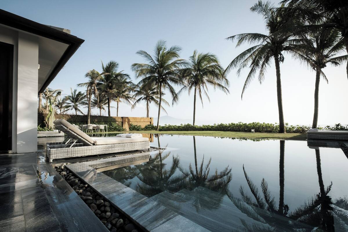 A modern pool area with a clear view of palm trees and a distant mountain range.
