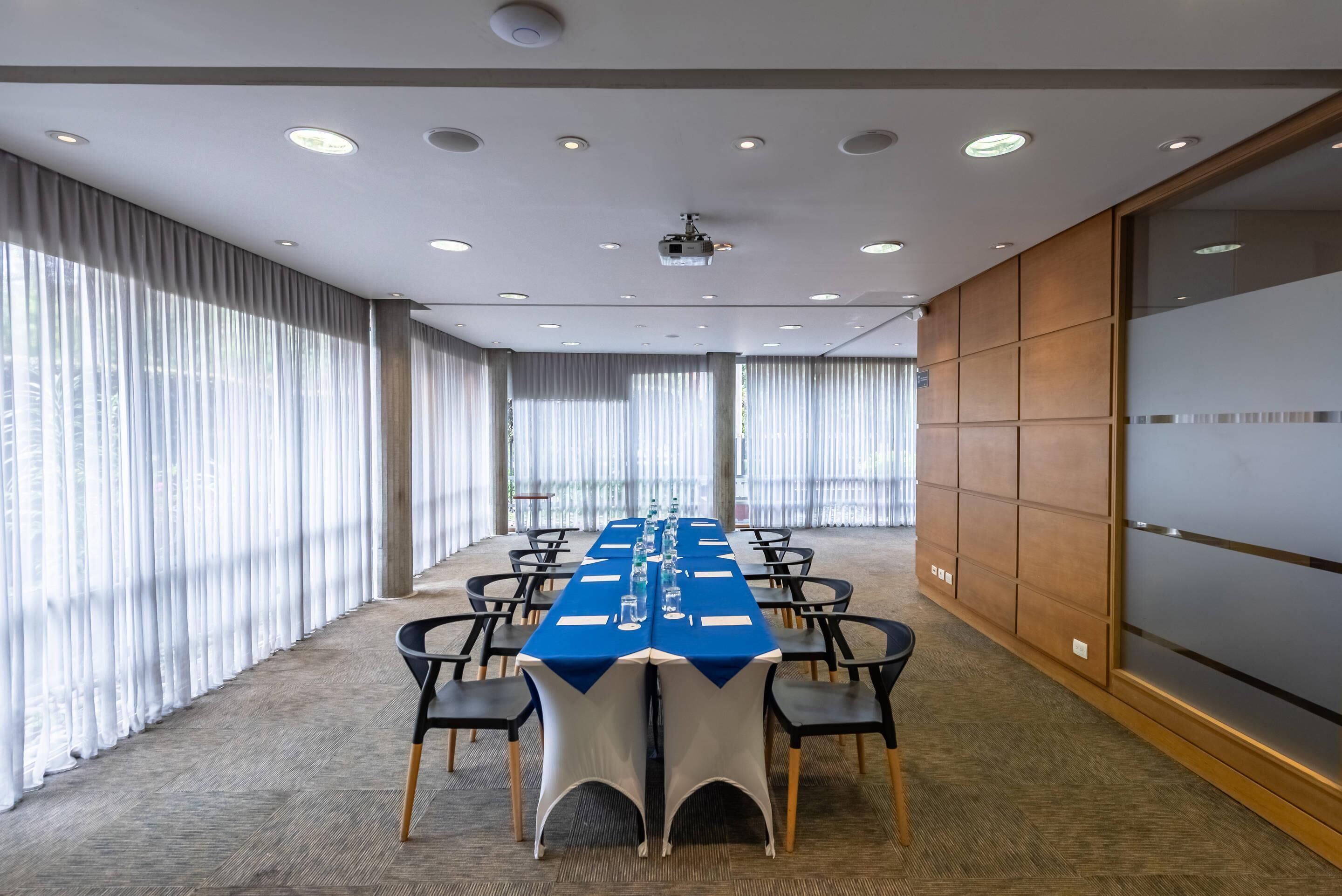 A conference room with a long table, chairs, and a projector.