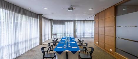 A conference room with a long table, chairs, and a projector.