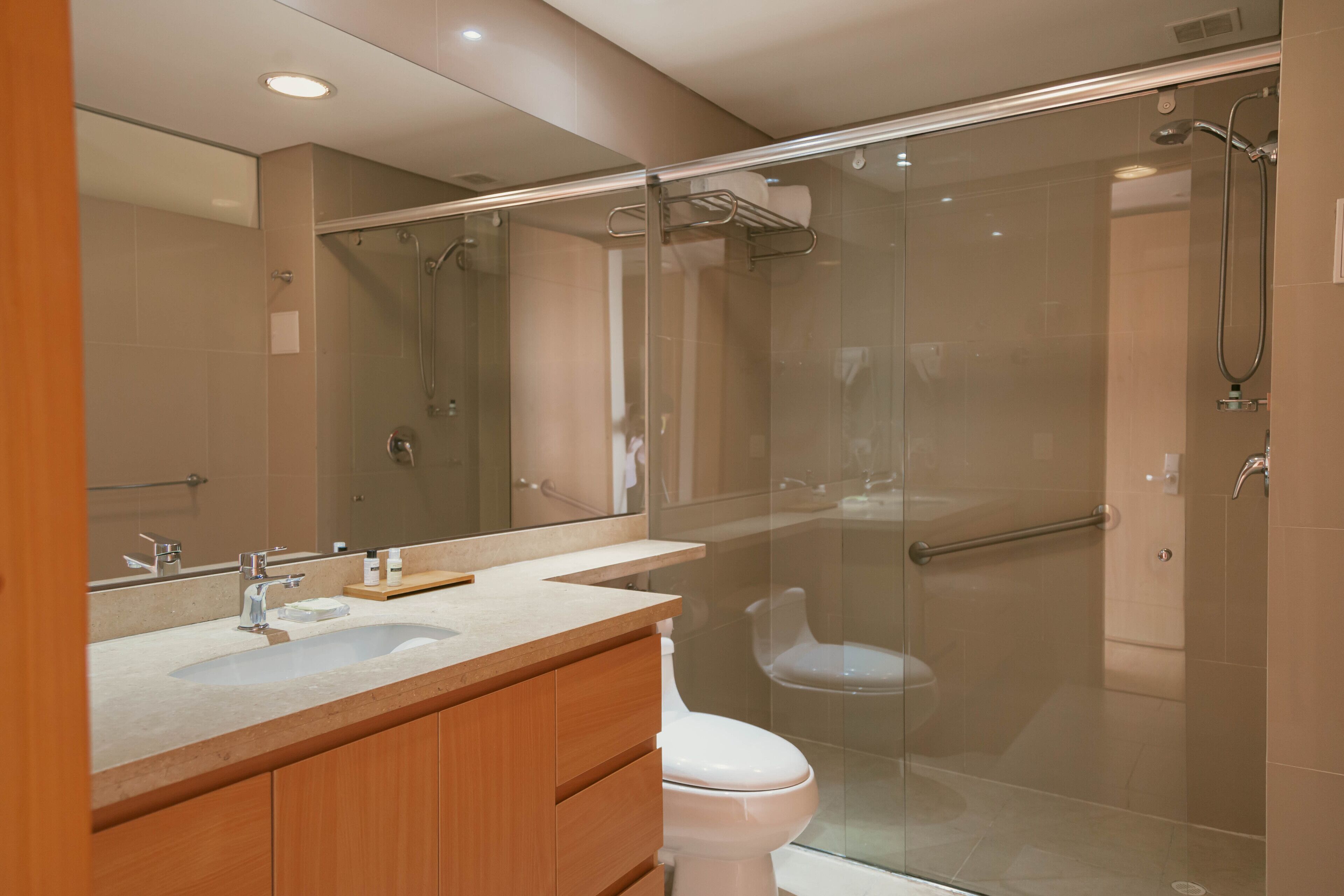 A modern bathroom with a glass-enclosed shower, a white sink, and a wooden vanity.